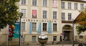 Das Linden-Museum Stuttgart soll an seinem bestehenden Standort umgebaut und erweitert werden: Geplant ist eine grundlegende Sanierung und Neukonzeption des Museumsgebäudes am Stuttgarter Hegelplatz einschließlich eines Erweiterungsbaus auf der gegenüberliegenden Seite entlang der Holzgartenstraße. Dies hat der Verwaltungsrat des Museums, in dem das Land Baden-Württemberg und die Landeshauptstadt Stuttgart vertreten sind, bei seiner Sitzung am 24. Juli  beschlossen. Pläne für ein komplett neues Museumsgebäude an einem anderen Standort, wie sie bislang diskutiert wurden, werden damit nicht weiterverfolgt.

„Das ist eine sehr gute Lösung. Das Linden-Museum erhält damit die Möglichkeit, sich neu aufzustellen und ein neues Museumskonzept umzusetzen – und das früher als mit dem bislang diskutierten Neubau auf dem S21-Areal“, sagte Staatssekretär Arne Braun. Der grundlegende Umbau ist nötig, da das denkmalgeschützte Museumsgebäude am Hegelplatz zahlreiche Defizite aufweist, die einer modernen Museumsarbeit im Wege stehen. „Die Neuaufstellung ist uns wichtig, da das Linden-Museum als ethnologisches Museum eine bedeutende gesellschaftliche und politische Rolle einnimmt“, sagte Arne Braun. Zugleich könne durch die Sanierung des Bestandsgebäudes ein relevanter Beitrag für den Klimaschutz erreicht werden – „grundsätzlich hat die Sanierung bestehender Gebäude Vorrang vor der Errichtung neuer Landesgebäude. Dazu hat das Land die Einrichtungen in staatlicher Hand in seinem Energie- und Klimaschutzkonzept verpflichtet“, so Braun. „Auch die Unterbringung des Depots unmittelbar am Standort wird geprüft werden“, sagte der Staatssekretär.

Bürgermeister Dr. Fabian Mayer: „Dieser Vorschlag verspricht, verschiedene Herausforderungen gleichzeitig zu lösen. Die konzeptionelle Ausrichtung des neuen ethnologischen Museums ist ein nachhaltiger Stuttgarter Weg, der Bestand und Tradition ebenso berücksichtigt wie einen von der kritischen Gegenwart getragenen Blick in die Zukunft.“ Dies eröffne weitere Perspektiven, sagte Mayer. „Mit der Sanierung am Standort wird sowohl das schwierige Erbe berücksichtigt als auch eine zeitlich naheliegendere bauliche Lösung gesucht. Auch städtebaulich steckt diese gemeinsame Richtung von Stadt und Land ein weiter gefasstes Kultur- und Bildungsareal in einem künftig größer gefassten Innenstadtbereich ab.“

Die Direktorin des Linden-Museums, Inés de Castro, sagte: „Für unser gesamtes Team ist diese Entscheidung sehr erfreulich und vor allem wichtig. Nun haben wir eine klare Perspektive und können die konkrete Planung für ein zukunftsfähiges Museum beginnen.“

Info: www.lindenmuseum.de

Das Völkerkundemuseum Linden-Museum in Stuttgart. (Foto: picture alliance/Sina Schuldt/dpa)